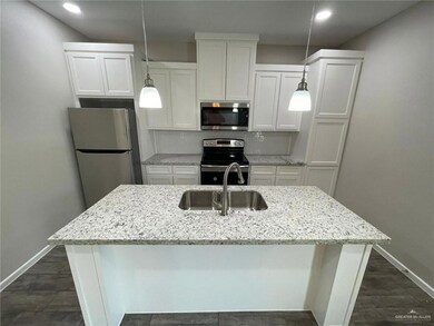Kitchen featuring appliances with stainless steel finishes, white cabinets, recessed lighting, a kitchen island with sink, and decorative light fixtures