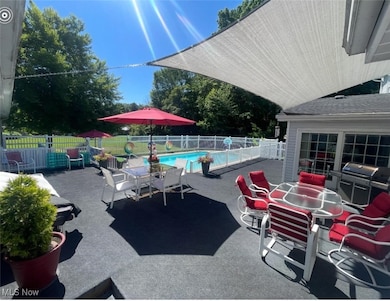 View of patio with a grill, outdoor dining area, and a community pool
