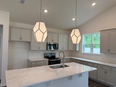 Kitchen featuring stainless steel appliances, gray cabinets, a sink, light stone countertops, and vaulted ceiling