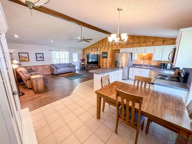 Dining area featuring a ceiling fan, a chandelier, wood walls, a textured ceiling, and light tile patterned floors