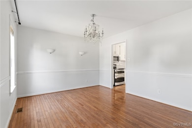 Empty room with a chandelier and hardwood / wood-s