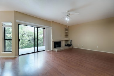 Unfurnished living room with ceiling fan, a tile fireplace, wood finished floors, and built in shelves