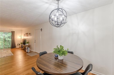 Dining room with a chandelier, light wood finished floors, and a textured ceiling
