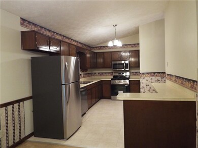 Kitchen featuring appliances with stainless steel finishes, dark brown cabinets, a peninsula, light countertops, and vaulted ceiling