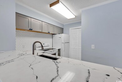 Kitchen featuring white appliances, gray cabinetry, a textured ceiling, light stone countertops, and ornamental molding