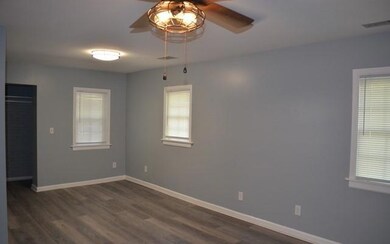 Empty room featuring ceiling fan, dark wood-type flooring, and baseboards