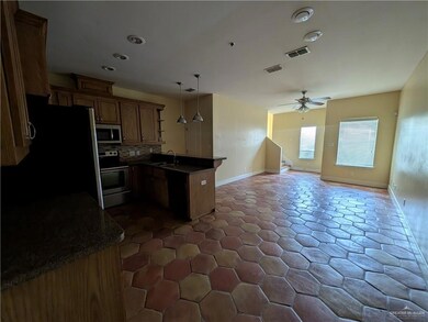 Kitchen featuring appliances with stainless steel finishes, dark countertops, a sink, a peninsula, and open floor plan