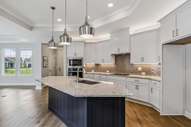 Kitchen featuring stainless steel appliances, sink, a raised ceiling, and light wood-type flooring