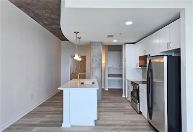Kitchen featuring freestanding refrigerator, a sink, electric range, light wood-type flooring, and hanging light fixtures