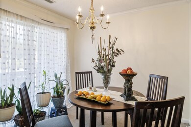 Carpeted dining space with crown molding and a cha