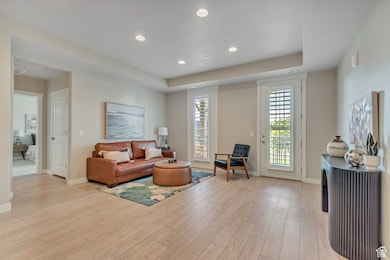 Living room with recessed lighting, light wood-style floors, and a raised ceiling