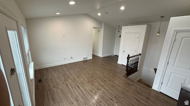 Interior space with vaulted ceiling, baseboards, dark wood-style floors, and recessed lighting