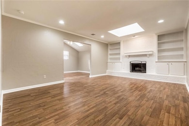 Unfurnished living room featuring a skylight, wood