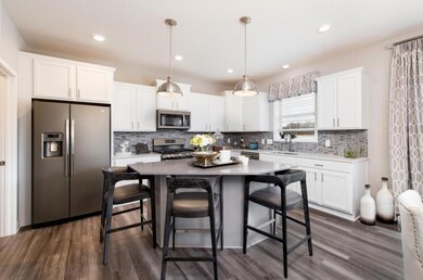 The open and bright modern kitchen is anchored by a large center island and is surrounded by expansive counter tops providing true eat in and entertaining capabilities! (model photo) Finishes will vary.