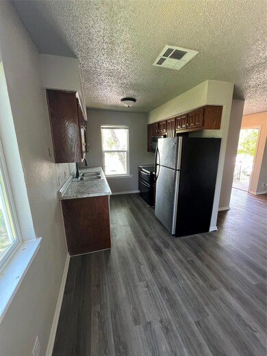 Kitchen featuring fridge, a textured ceiling, bas