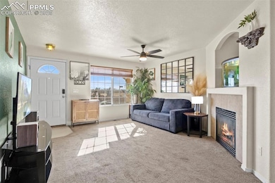 Living room featuring ceiling fan, a tile fireplac