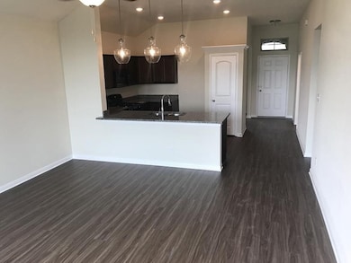 Kitchen featuring dark stone counters, dark wood-s