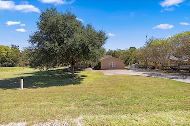 View of grassy yard featuring concrete driveway an
