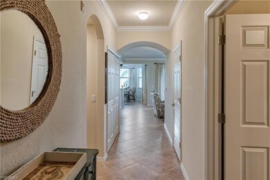 Hall with crown molding, light tile patterned floors, arched walkways, and a textured wall