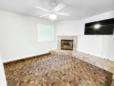 Unfurnished living room with carpet flooring, a tile fireplace, and a ceiling fan