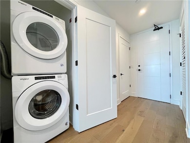 Laundry area featuring stacked washer / dryer, light wood-style flooring, and recessed lighting