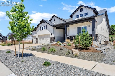 Modern farmhouse style home featuring board and batten siding, driveway, roof with shingles, and stone siding