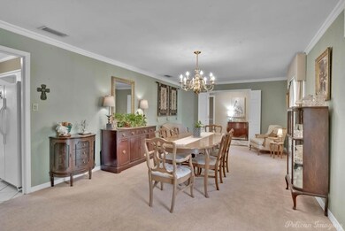 Carpeted dining room featuring crown molding and a