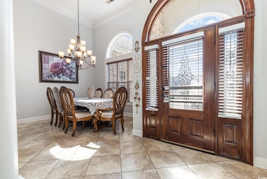 Foyer with crown molding, light tile patterned floors, and a chandelier