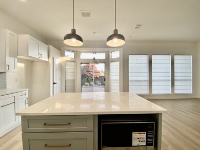 Kitchen with light wood-style floors, decorative light fixtures, and white cabinetry