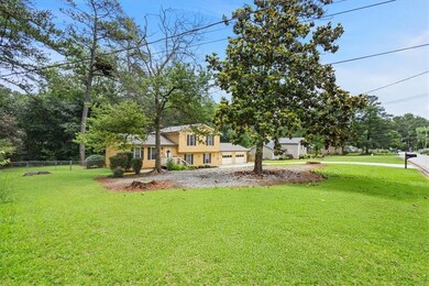 View of yard featuring a garage, driveway, and view of wooded area
