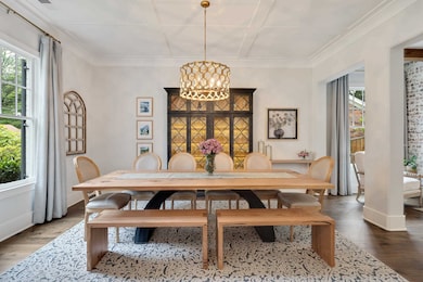 Dining area featuring wood finished floors, a chandelier, baseboards, ornamental molding, and coffered ceiling