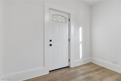 Foyer featuring light wood-style flooring and baseboards