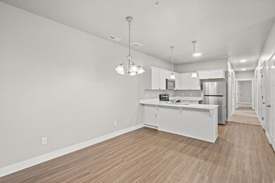 Kitchen featuring white cabinets, appliances with stainless steel finishes, a peninsula, a chandelier, and a breakfast bar