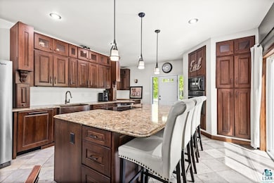 Kitchen with a sink, a kitchen breakfast bar, a center island, glass insert cabinets, and light stone countertops