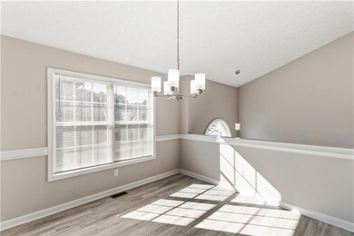 Unfurnished dining area with a chandelier, wood finished floors, vaulted ceiling, and a textured ceiling