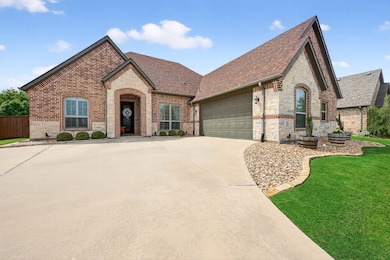 French provincial home with stone siding, roof with shingles, brick siding, an attached garage, and a front lawn