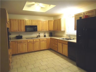 The kitchen features tile flooring and an abundance of custom cabinetry with black appliances including the refrigerator.  
