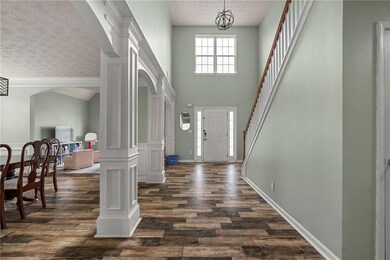 Foyer featuring a textured ceiling, dark wood finished floors, arched walkways, stairs, and a towering ceiling