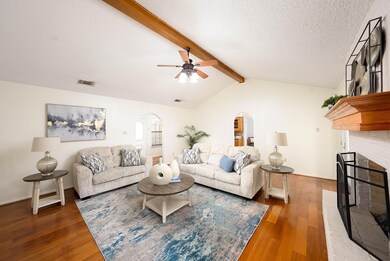 Living room featuring arched walkways, a fireplace, dark wood finished floors, a textured ceiling, and a ceiling fan