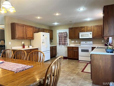 Kitchen featuring light countertops, white appliances, recessed lighting, decorative light fixtures, and brown cabinetry