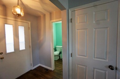 View of the front door, half bath and door to the 