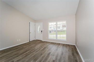 Unfurnished living room featuring dark wood-style floors and lofted ceiling