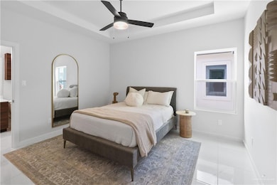 Bedroom with a tray ceiling, light tile patterned floors, a ceiling fan, and baseboards