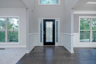 Entryway featuring wainscoting, visible vents, a decorative wall, and dark wood-style floors