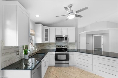Kitchen with dark stone counters, white cabinetry,