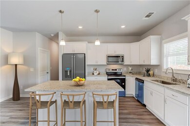 Kitchen with stainless steel appliances, a sink, a center island, white cabinetry, and recessed lighting