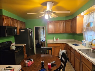 Kitchen featuring ceiling fan, black electric range oven, sink, and light tile patterned flooring