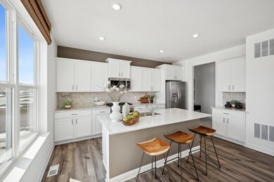 (Photo of model home, finishes will vary) Welcome to the Burnham! This spacious kitchen includes a large center island, quartz countertops, recessed lighting, LVP wood floors, stainless appliances and more.