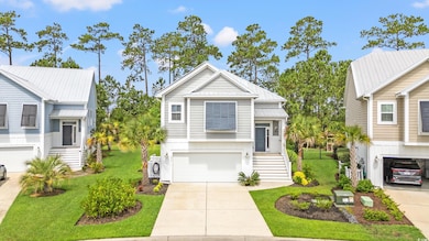 View of front facade featuring an attached garage, concrete driveway, a front yard, stairs, and a metal roof