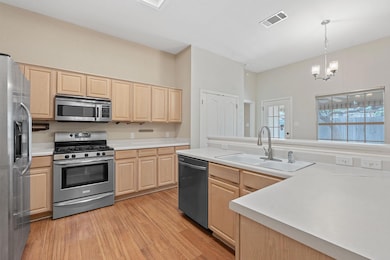 Kitchen with light brown cabinets, stainless stee